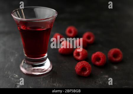 rich alcoholic raspberry tincture in a stack with fresh raspberries Stock Photo