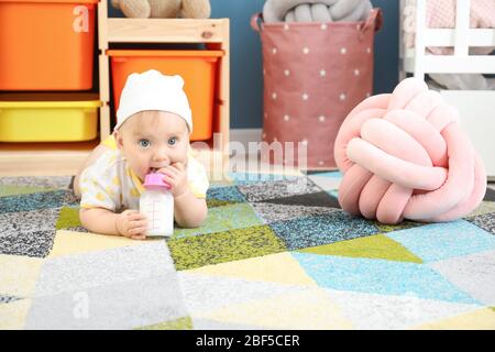 Cute baby drinking milk from bottle at home Stock Photo