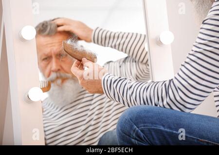 Senior man with hair loss problem near mirror Stock Photo