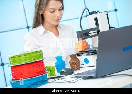 Young female designer works with a 3D printer in a design studio Stock Photo