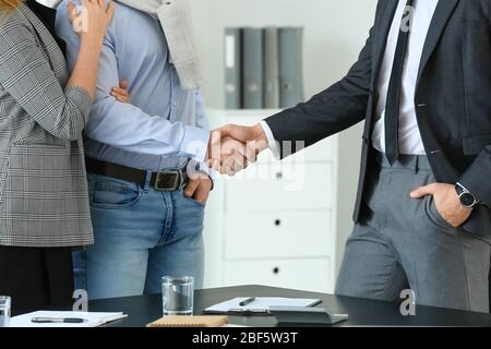 Bank manager and clients shaking hands in office Stock Photo