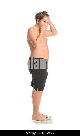 Overweight boy standing on scales against white background Stock Photo