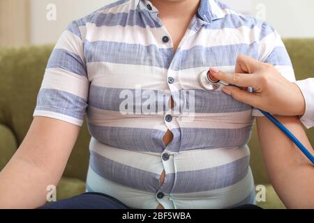 Doctor examining fat boy in clinic Stock Photo