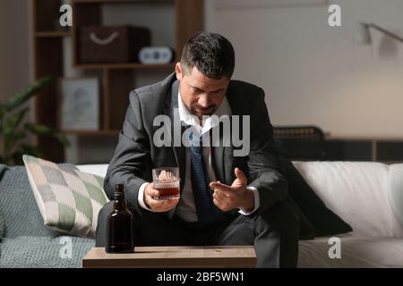 Divorced man drinking cognac at home. Concept of alcoholism Stock Photo