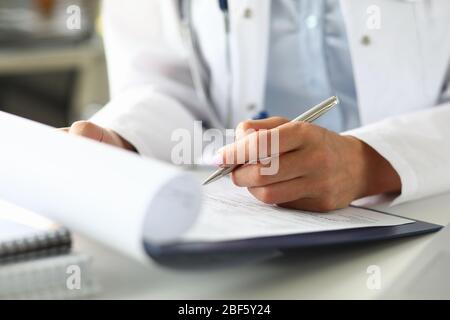 Hands of female GP making notes with silver pen Stock Photo