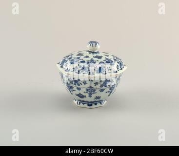 Bowl and lid. Eight-sided bowl on short foot; domed cover with ball finial; painted in underglaze blue on white, around body with Chinese pots and border of floral reserves, on cover with matching design, on finial with flower. Stock Photo