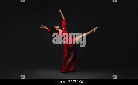 Contemporary female dancer performing over black background. Young woman dancing in studio. Stock Photo