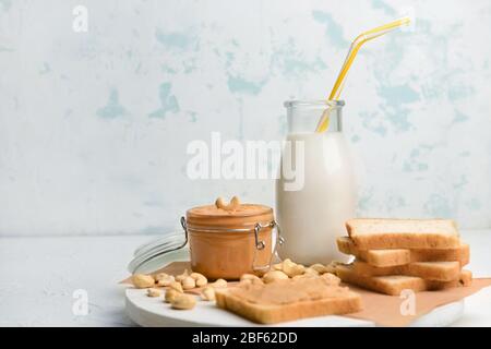 Bottle of cashew milk and bread with nut butter on white background Stock Photo