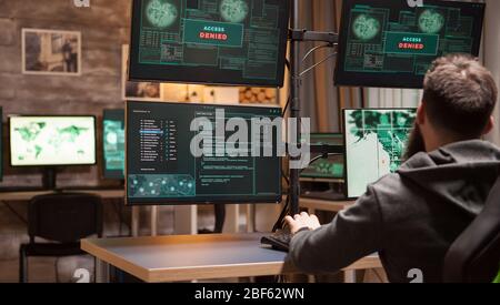 Back view of male hacker gets access denied while trying to plant a malware. Stock Photo