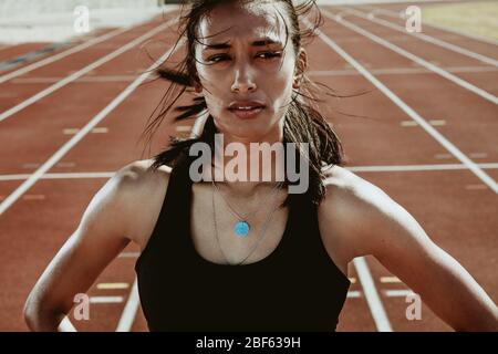 Confident sportswoman standing with her hands on hips and looking away.  Fitness girl with headphones on taking break after workout Stock Photo -  Alamy