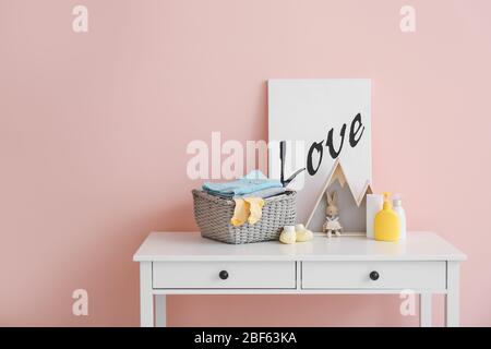 Baby clothes with cosmetics and toy on table in room Stock Photo