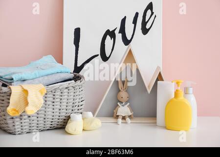 Baby clothes with cosmetics and toy on table in room Stock Photo