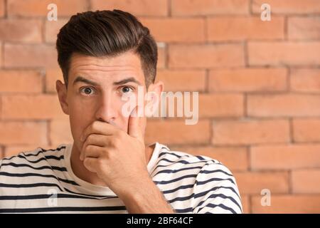 Worried young man on brick background Stock Photo