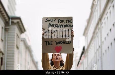 Young woman holding poster and protesting. Demonstrator making protest about climate change. Stock Photo