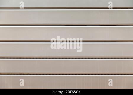 Close-up on a radiator composed of horizontal heating panels. They are white and worn and have interstices made up of small holes Stock Photo