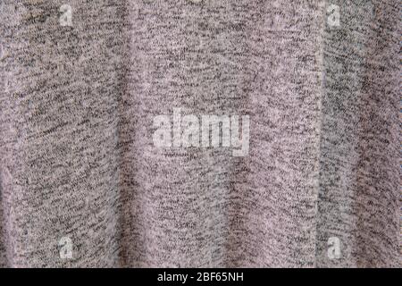 Close-up on the folds of a gray tracksuit hanging on a hanger. The visible patterns of the falling fabric form destructured shadows Stock Photo