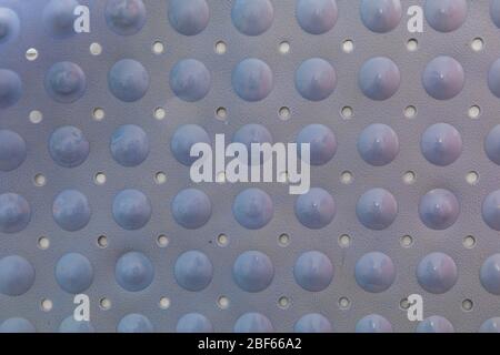 Close-up of a blue plastic bath mat made of bubbles and holes to prevent skidding. It is glued to the wall and lit with natural light. Stock Photo
