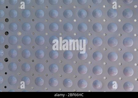 Close-up of a blue plastic bath mat made of bubbles and holes to prevent skidding. It is glued to the wall and lit with natural light. Stock Photo