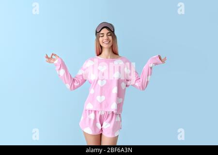 Portrait of meditating woman in pajamas and with sleep mask on color background Stock Photo