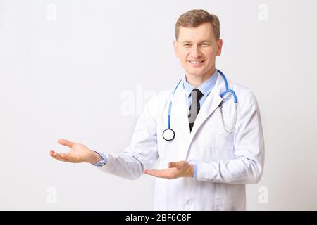 Male cardiologist showing something on light background Stock Photo