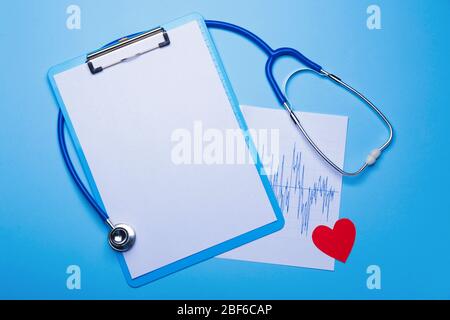 Stethoscope, heart, clipboard and cardiogram on color background Stock Photo