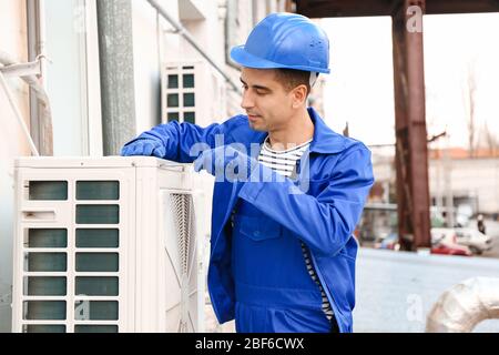 Male technician installing outdoor unit of air conditioner Stock Photo