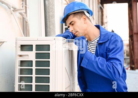Male technician installing outdoor unit of air conditioner Stock Photo