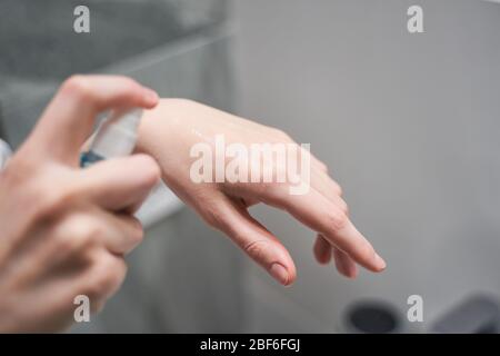 Woman using an alcohol-based hand sanitizer indoors Stock Photo