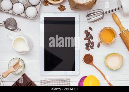 Ingredients and tools for baking and tablet with blank screen and place for text or image on white table Stock Photo