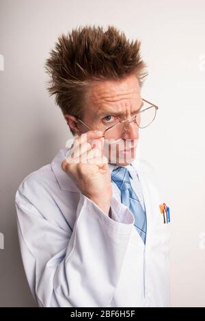 Skeptical scientist lowering his glasses to look at the camera with a doubtful expression Stock Photo