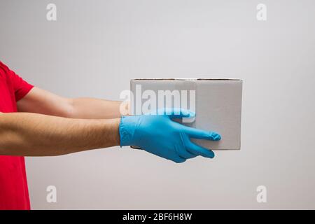 Delivery man holding cardboard boxes in protective rubber gloves. Stock Photo