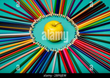 Office background. Apple and colored pencils are laid out in a circle  Stock Photo