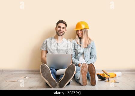 Young couple with laptop planning repair of their new apartment Stock Photo