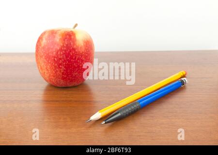 An apple with pencils is on the table, a white background. Stock Photo