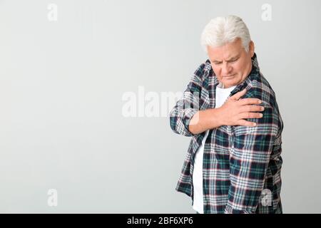 Senior man suffering from Parkinson syndrome on grey background Stock Photo