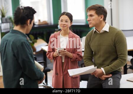 Group of young business people with documents standing at office and working in team Stock Photo