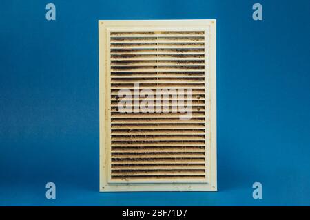Extremely dirty and dusty white plastic ventilation grill for the home on a blue background. Hygiene. Stock Photo