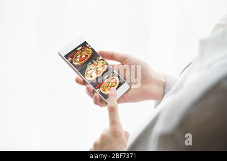 Unrecognizable woman is holding cell phone. View from behind, mockup Stock Photo