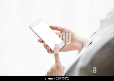 Unrecognizable woman is holding cell phone. View from behind, mockup Stock Photo