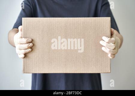 Contactless delivery of online order to door of house, hands in sterile rubber gloves Stock Photo