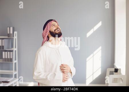Attractive smiling arab man laughing rejoices standing in a modern office Stock Photo