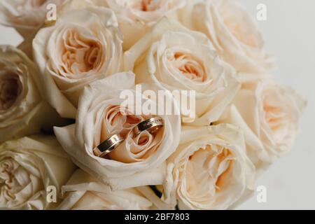 Gold wedding rings lying on the bouquet of the roses Stock Photo