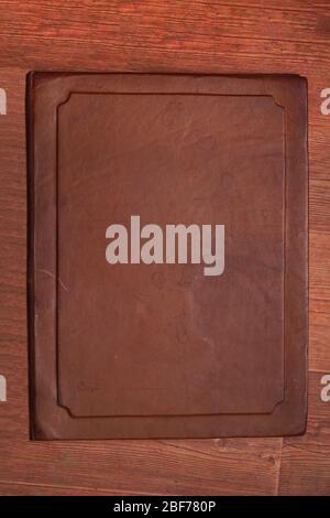 Antique brown aged leather cover with different spots on a wooden brown background Stock Photo