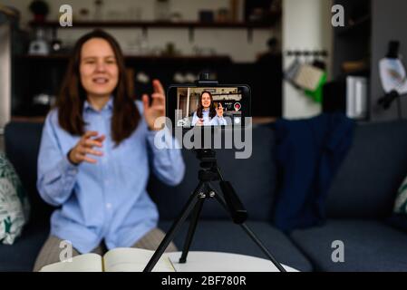 Woman in shirt Recording video at home for her video blog. Using smartphone Stock Photo