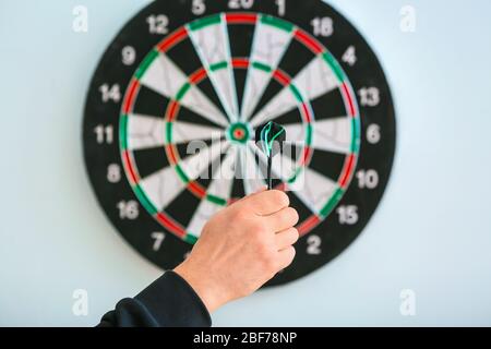 Young man playing darts indoors Stock Photo