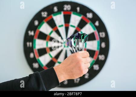 Young man playing darts indoors Stock Photo