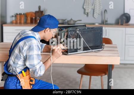 Worker repairing microwave oven in kitchen Stock Photo