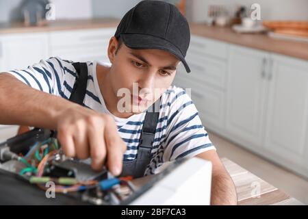 Worker repairing microwave oven in kitchen Stock Photo