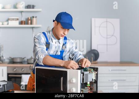 Worker repairing microwave oven in kitchen Stock Photo