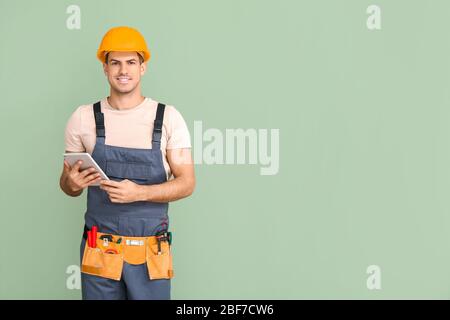 Handsome male worker with tablet computer on color background Stock Photo